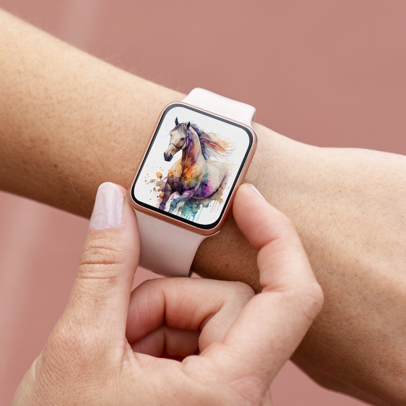 May include: A white smartwatch with a rose gold band displays a colorful watercolor painting of a horse running. The horse is white with splashes of pink, blue, and green.