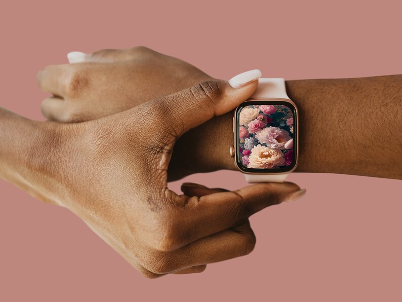 May include: A white smartwatch with a rose gold band and a floral screen saver. The watch is on a person's wrist.