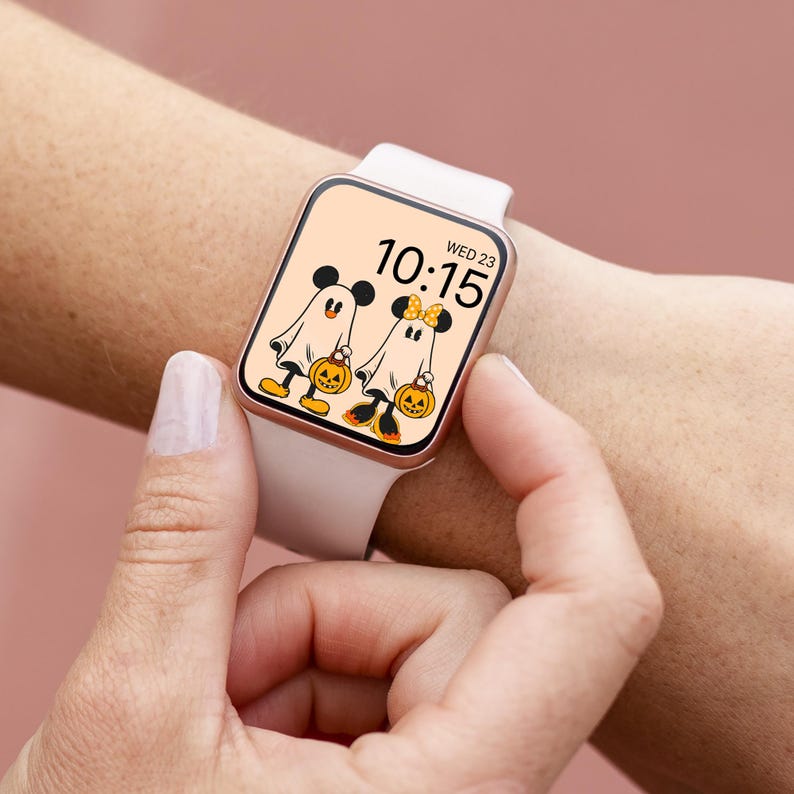May include: A white smartwatch with a rose gold band displays a Halloween-themed watch face featuring Mickey Mouse and Minnie Mouse dressed as ghosts carrying jack-o'-lanterns. The time is 10:15 and the date is WED 23.