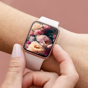 May include: A white smartwatch with a rose gold band and a floral screen saver. The screen saver features a close-up of pink, white, and yellow flowers.