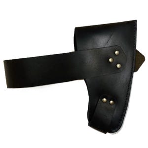 May include: Black leather axe sheath with a wide belt loop and a smaller strap secured with silver-colored rivets. The sheath is designed to hold an axe head and protect the blade.