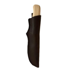May include: A wooden-handled knife partially inserted into a dark brown leather sheath. The knife handle is light-colored wood, and the sheath is a darker, solid brown. The sheath has a curved design and stitched edges.
