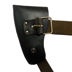 May include: Black leather axe sheath with a brown strap and silver buckle. The sheath has a riveted design and a snap closure. The axe sheath is designed to protect the axe blade.