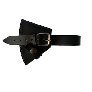May include: Black leather axe sheath with a buckle closure and a snap closure. The sheath has a belt loop and is designed to hold an axe. The leather is smooth and the hardware is silver-colored.
