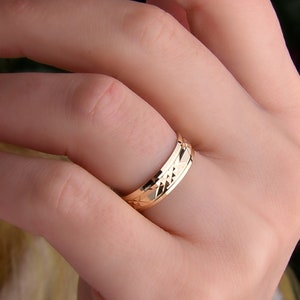 May include: A gold wedding band with a diamond-shaped pattern.
