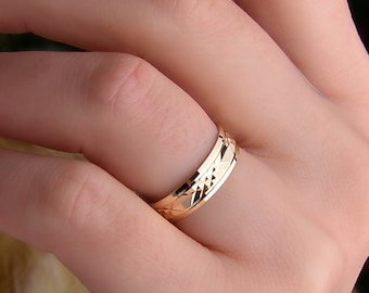 May include: A gold wedding band with a diamond-shaped pattern.
