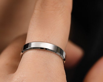 May include: A silver band ring with a beveled edge.