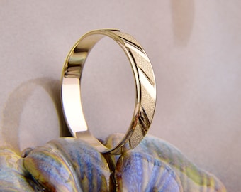 May include: A gold wedding band with a textured, diamond-cut design.