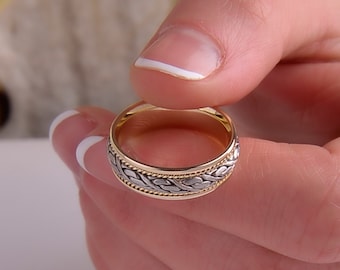 May include: A gold and silver wedding band with a braided design.
