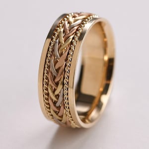 Puede incluir: Una alianza de oro con un diseño trenzado en tres tonos de oro.
