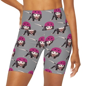 Könnte beinhalten: Graue Sport-Shorts mit einem sich wiederholenden Muster aus Opossums, die rosa Helme tragen. Die Opossums sind alle nach vorne gerichtet und haben den Mund offen.