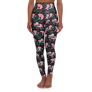 Könnte beinhalten: Schwarze Yoga-Leggings mit einem pinkfarbenen und blauen Rollschuh-Muster. Das Muster enthält Herzen, Sterne und Rollschuhe.