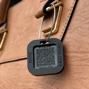 May include: Black luggage tag with a QR code and the words "If Found", "Name", "Last Name", and "Scan Me". The tag is attached to a brown leather bag with a metal clasp.