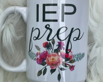 Può includere: Tazza in ceramica bianca con testo nero che recita "IEP prep" e un design floreale in tonalità rosa, arancio e verde.