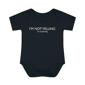 May include: A black baby onesie with white text that reads "I'M NOT YELLING I'm projecting".