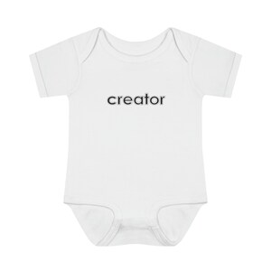 May include: White baby onesie with short sleeves and the word "creator" printed in black on the front.