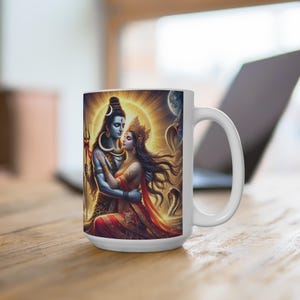 May include: White ceramic mug with a colorful image of Shiva and Parvati, Hindu deities, embracing in a loving pose. The image is surrounded by a golden halo and intricate details.