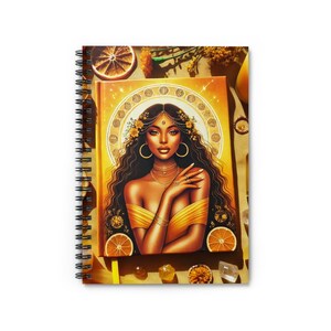 May include: A spiral bound notebook with a yellow and gold cover featuring a digital illustration of a woman with a crown of flowers and a golden halo. The woman is wearing a yellow dress and has dark brown hair and eyes. The background is a yellow and gold color.