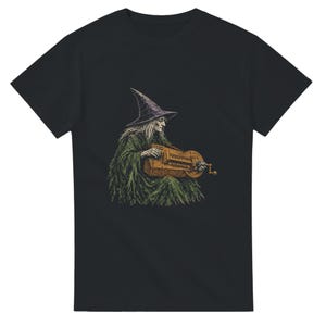 May include: A black short-sleeved t-shirt featuring a graphic illustration of a figure wearing a pointed hat and a textured green robe, playing a wooden hurdy-gurdy instrument. The design is centred on the chest of the garment.