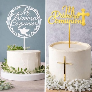 Puede incluir: Dos pasteles blancos decorados para una celebración religiosa. Uno presenta un adorno blanco con el texto "Mi Primera Comunión" y una paloma. El otro tiene un adorno de cruz dorada y una cruz dorada en el pastel. Ambos pasteles están decorados con vegetación y flores.