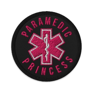 Può includere: Toppa rotonda nera ricamata con le parole "PARAMEDIC PRINCESS" in filo rosa. Il centro presenta un emblema rosa della Stella della Vita con un bastone bianco di Asclepio.