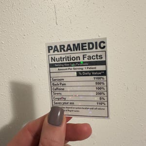 Puede incluir: Una pegatina con el texto "PARAMEDIC Nutrition Facts" enumera los valores diarios para el trabajo de un param&eacute;dico, incluyendo sarcasmo, dolor de espalda, cafe&iacute;na, sirenas, empat&iacute;a y "Saves your ass".