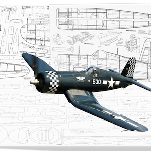 Puede incluir: Un avión modelo azul y blanco con el número 530 en el lateral. El modelo es una réplica de un avión de combate de la Segunda Guerra Mundial. El modelo está sobre un conjunto de planos del avión.