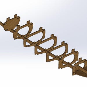 Könnte beinhalten: Ein Holzmodell eines Bootsrahmens mit mehreren gebogenen Abschnitten und rechteckigen Laschen. Die Teile sind diagonal angeordnet und zeigen die innere Struktur des Bootsdesigns. Das Holz hat eine natürliche, hellbraune Farbe.