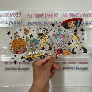 Puede incluir: Una lámina de pegatinas transparente con personajes de dibujos animados y detalles de estrellas negras. La lámina incluye personajes en amarillo, verde, rojo y rosa. El texto "ALL THINGS LABELED with mouse magic" es visible.