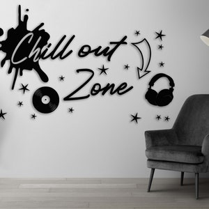 Puede incluir: Pegatina de pared en blanco y negro con el texto "Chill out Zone" y un disco, auriculares y estrellas. En el fondo se ve un sillón negro y una lámpara de pie.