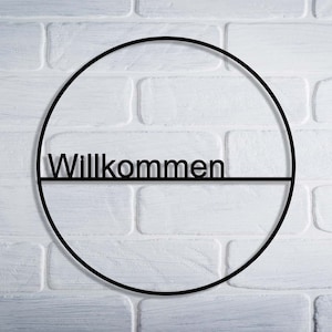 May include: A black metal circle with the word "Willkommen" written across the center.