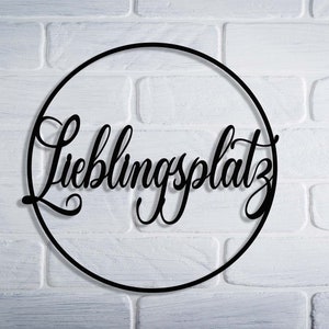 May include: Black metal circle with the German words "Lieblingsplatz" written in a decorative script.