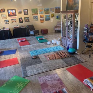 May include: A yoga studio with a variety of yoga mats, meditation cushions, and singing bowls. The studio is decorated with artwork and has a calming atmosphere.