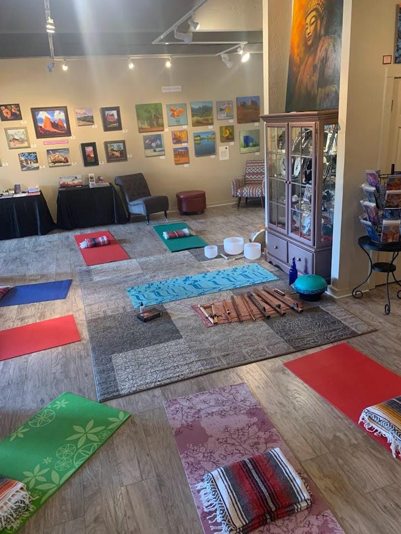 May include: A yoga studio with a variety of yoga mats, meditation cushions, and singing bowls. The studio is decorated with artwork and has a calming atmosphere.