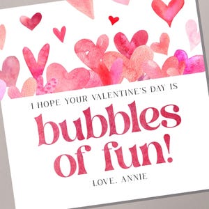 May include: A white card with pink watercolour hearts at the top. The text reads "I hope your Valentine's Day is bubbles of fun! Love. Annie."