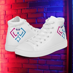 Puede incluir: Par de zapatillas altas blancas con un diseño geométrico colorido en el lateral. Las zapatillas tienen cordones y suelas blancas. El fondo es una pared de ladrillo con iluminación roja y azul.