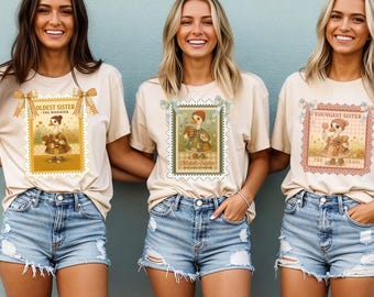 May include: Three women wearing beige t-shirts with vintage-style postage stamp designs. Each shirt features a different illustration of a duck in a dress, with text indicating "Oldest Sister," "Middle Sister," and "Youngest Sister." They are wearing denim shorts.