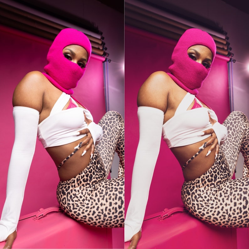 Op de afbeelding: Een persoon draagt een felroze bivakmuts, een witte crop top en een legging met luipaardprint. De persoon draagt ook witte armmouwen. De achtergrond is felroze.