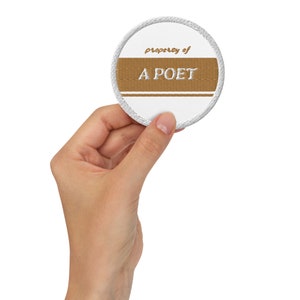 May include: A white round patch with a brown stripe and the text "property of A POET" in white.