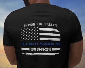 May include: Black t-shirt with a white and blue American flag design. The text "HONOR THE FALLEN" is above the flag. Below the flag is the text "SGT MATT MAINIERI #155 EOW 09-03-2018".