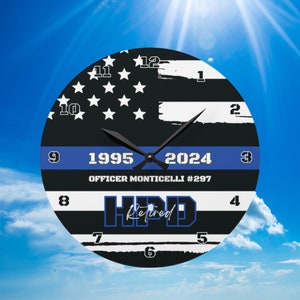 May include: A black and white clock with a blue line and stars. The clock face has the text "1995" and "2024" with "OFFICER MONTICELLI #297" and "HPD Retired" below. The clock hands are pointing to 12:00.