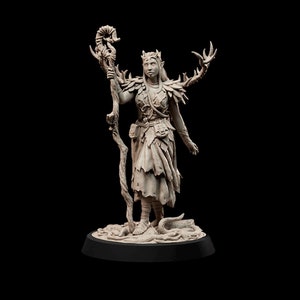 Peut inclure: Une figurine miniature détaillée d'une elfe avec une couronne de bois de cerf, portant une robe feuillue et tenant un bâton surmonté d'un crâne. La figurine est peinte en brun clair et repose sur une base circulaire.
