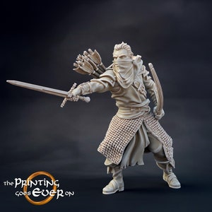 以下が含まれることがあります： フード付きのマントを着て、剣と弓矢を持った人物のミニチュアフィギュア。フィギュアは薄い茶色のプラスチック製で、黒い背景の上に立っています。