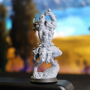 May include: A grey, detailed miniature figurine of a beast-like creature with a spiked club, wearing armour and a belt with skulls. The figurine is posed in a dynamic action pose.