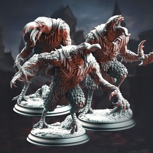 Puede incluir: Tres esculturas detalladas de criaturas humanoides aviares con picos afilados, garras y cuerpos emplumados. Las figuras están posadas sobre bases redondas y blancas, con un fondo oscuro y borroso que sugiere un entorno gótico. Las esculturas son en tonos marrones y grises.