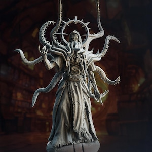 Puede incluir: Una detallada escultura gris de una criatura mítica con corona, tentáculos y una túnica fluida. La figura tiene una apariencia esquelética y está posada con los brazos extendidos. El fondo es un interior borroso con detalles arquitectónicos.