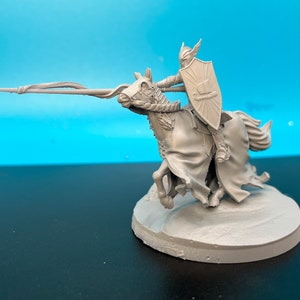 May include: A gray plastic miniature of a knight riding a horse, holding a spear and shield. The knight is wearing a helmet and armor. The horse has a flowing mane and tail. The miniature is on a round base.