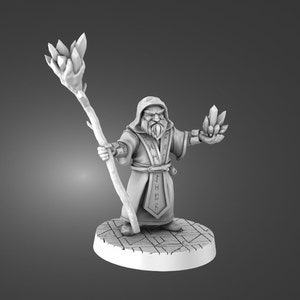 Op de afbeelding: Een wit miniatuurbeeldje van een dwergtovenaar die een staf vasthoudt met een kristal aan de bovenkant en een kristal in zijn andere hand. Hij draagt een gewatteerde mantel met runen erop. Het beeldje staat op een ronde basis met een gepatroneerd ontwerp.