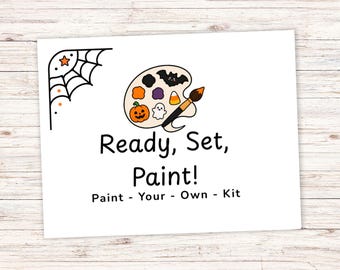 May include: A white rectangular card featuring a black spiderweb corner design with an orange star. A central illustration shows a paint palette with a bat, pumpkin, ghost, and candy corn, plus a paintbrush. Text reads: Ready, Set, Paint! Paint - Your - Own - Kit.
