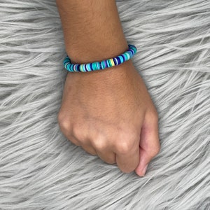 May include: A colorful bracelet made of stacked, round, plastic beads in shades of blue, green, and yellow.